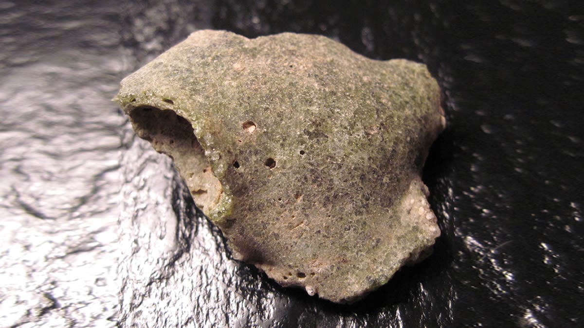 Fragmento de trinitita formado en la prueba nuclear Trinity, vidrio verdoso asociado a cuasicristales